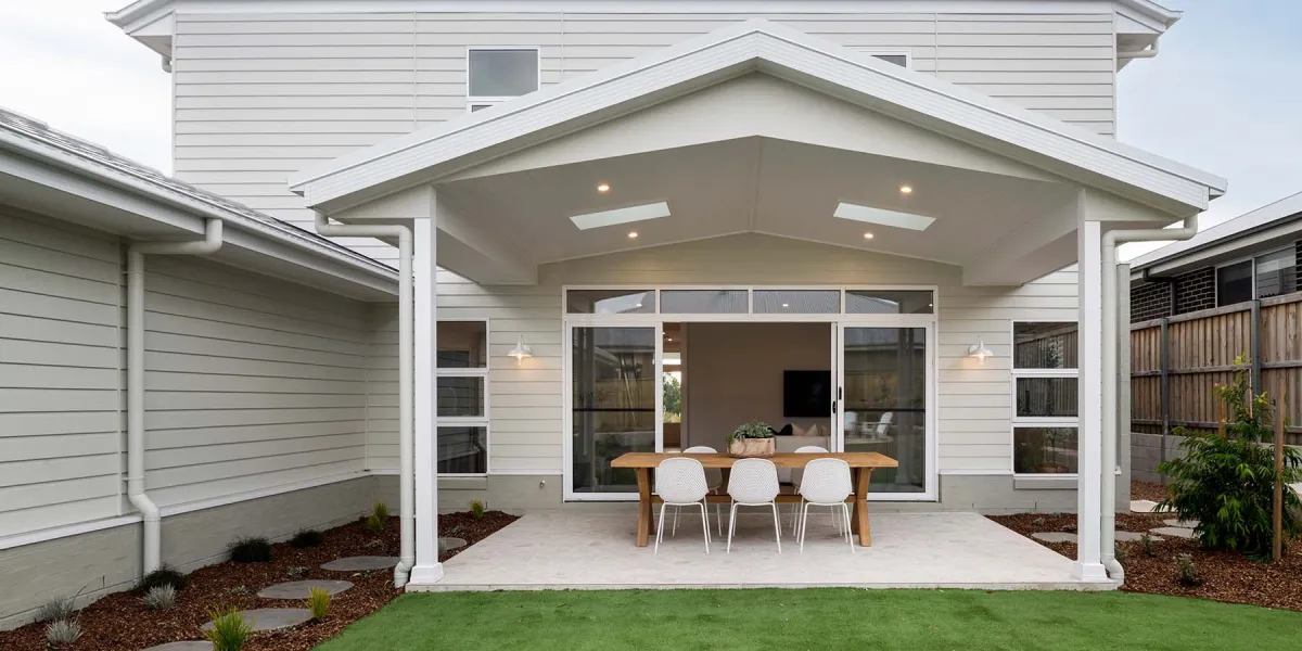 Hamptons-style alfresco area with wicker chairs and a timber table.